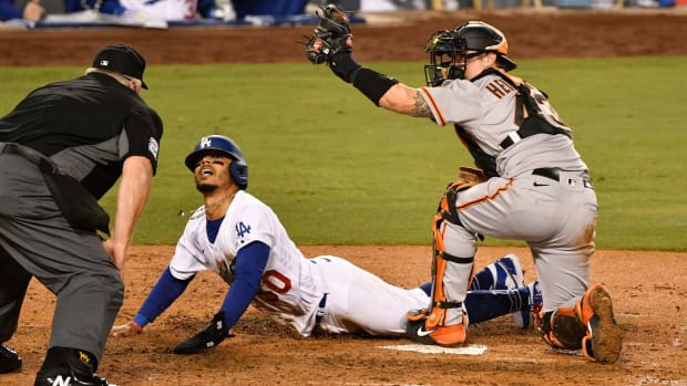 Jul 23, 2020; Los Angeles, California, USA; Los Angeles Dodgers right fielder Mookie Betts (50) looks up at umpire Bill Miller (left) as San Francisco Giants catcher Tyler Heineman holds up the ball during the seventh inning at Dodger Stadium. Betts was called safe after a video review. Mandatory Credit: Robert Hanashiro-USA TODAY Sports